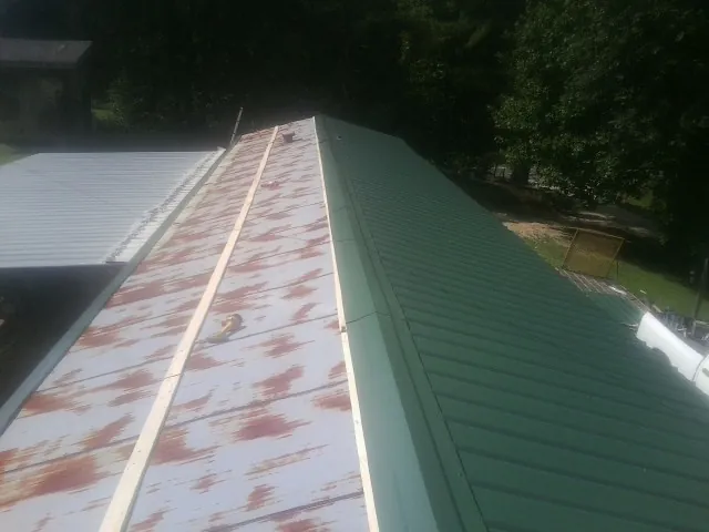 Old rusted panels beside newly installed green metal roofing — Wind Damage Roof Repair by Roofing Brothers in Maple Park
