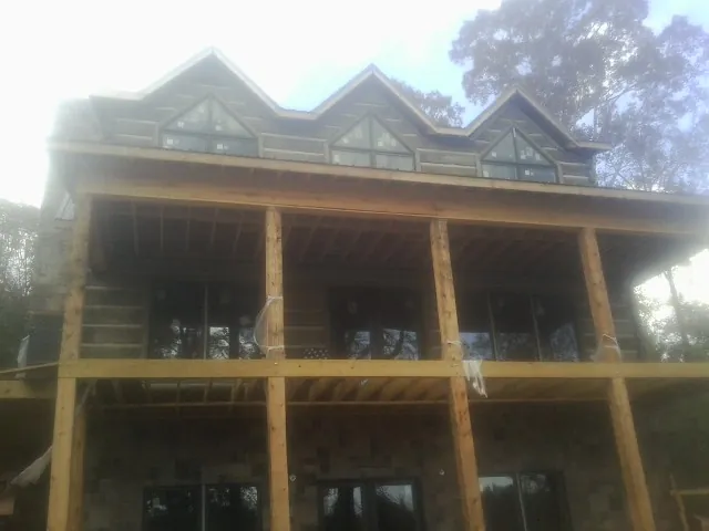 Dormers and porch framing on a large log home under construction — Roof Coating work by our crew in Maple Park