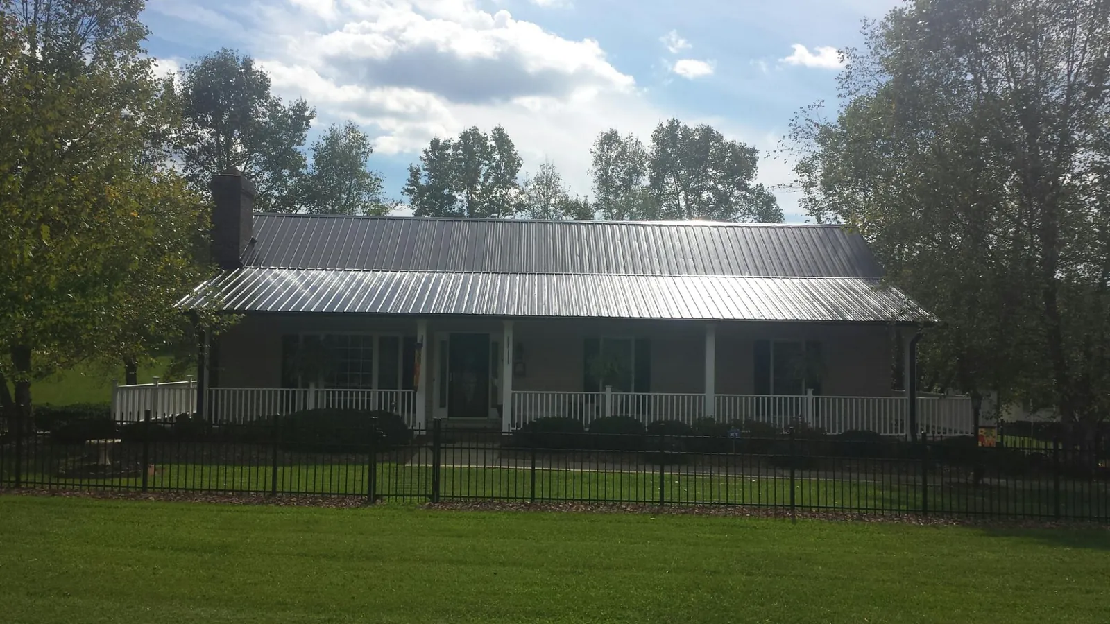 Gray metal roof on a brick ranch with a full width front porch — Gutter Guard Installation work by our crew in Maple Park
