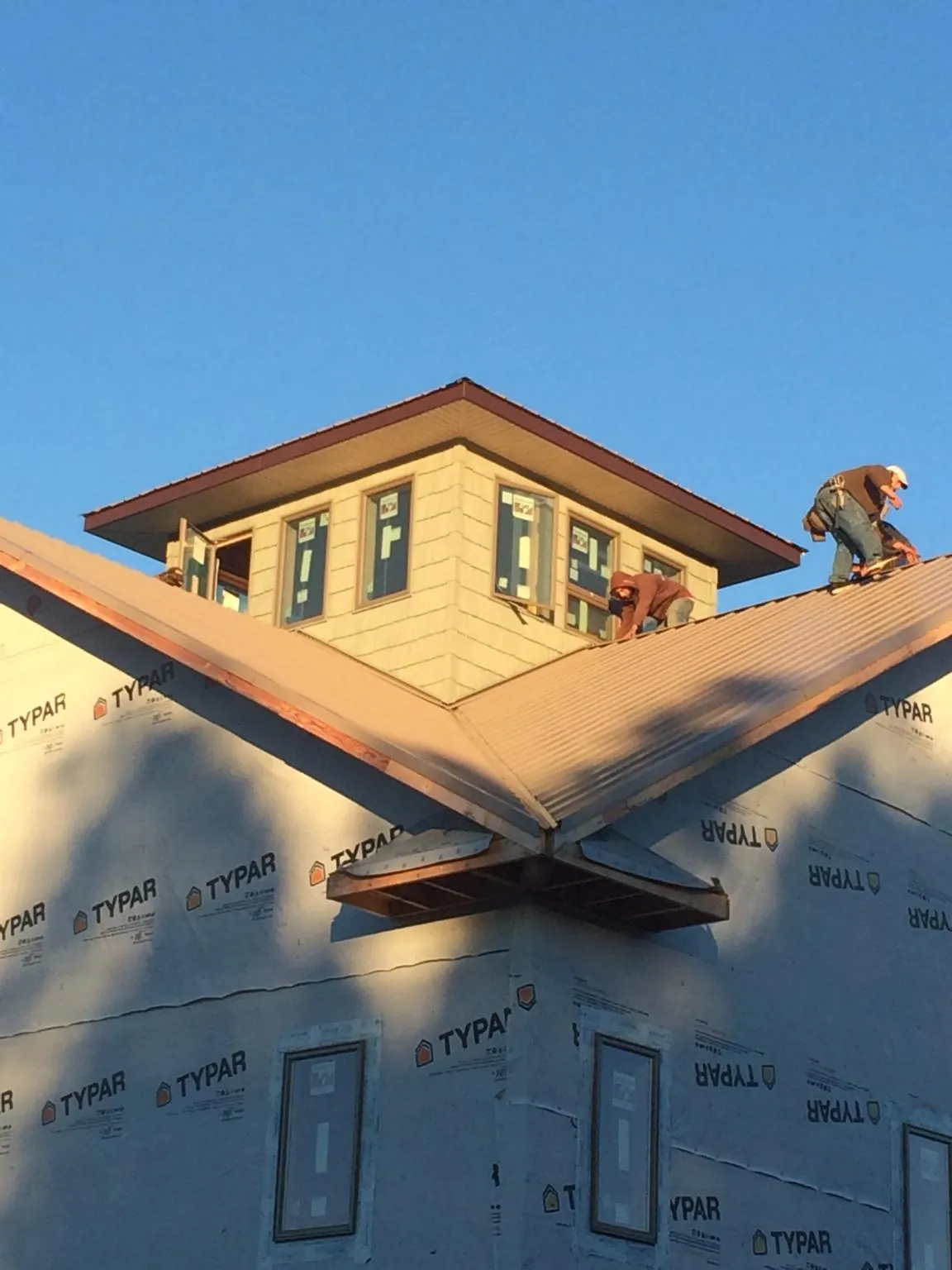 Roofers working around a rooftop cupola on a new metal roof at sunset — Roof Waterproofing in Maple Park by Roofing Brothers